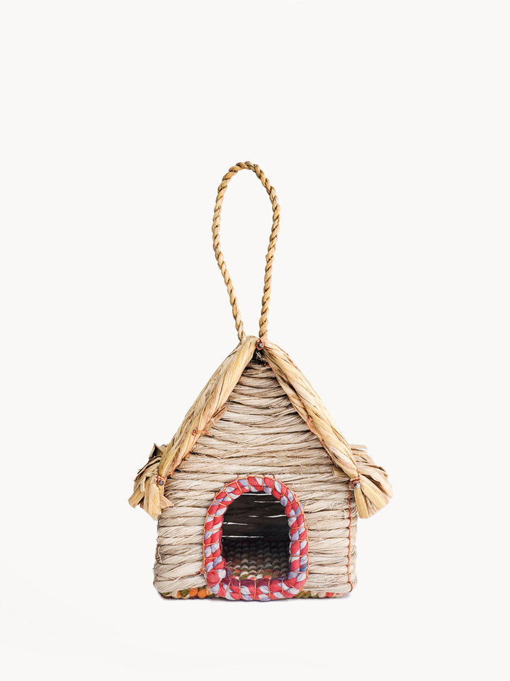 Cabin-style seagrass birdhouse with peaked thatched roof and sari-trimmed arched entry
