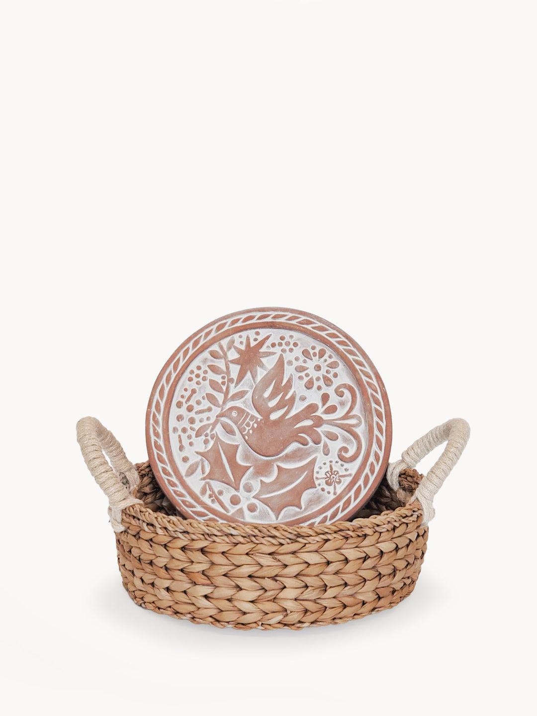 Round terracotta bread warmer engraved with a bird design in a woven seagrass basket