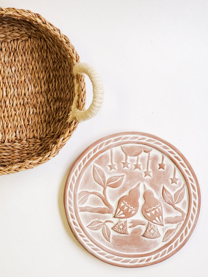 Terracotta lovebirds plate resting in its round seagrass bread basket