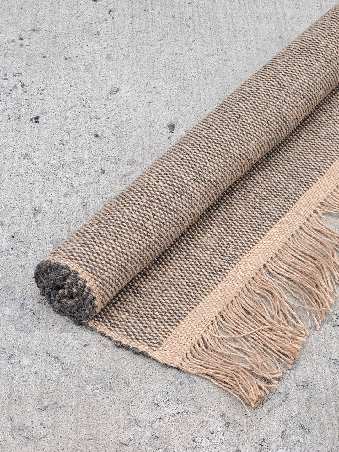 Gray braided jute floor rug, fringed and hand-loomed in Bangladesh