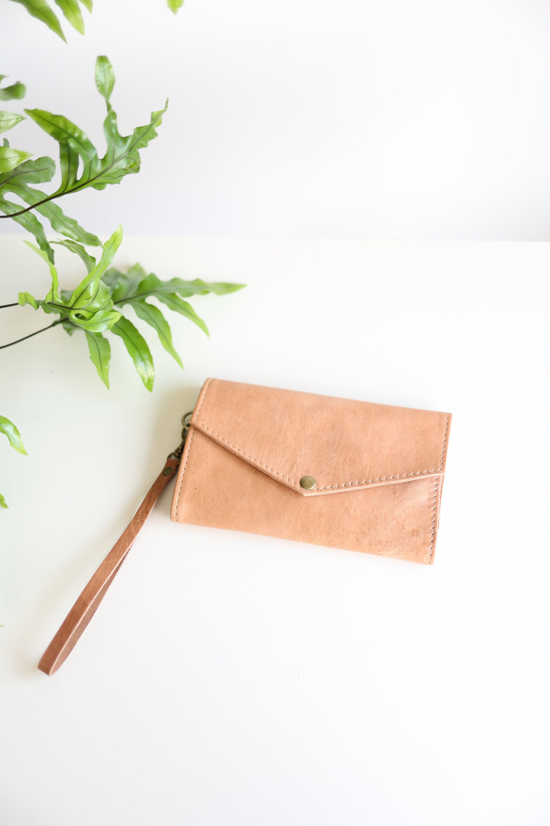 Handmade leather wristlet wallet with card slots and a wrist strap.