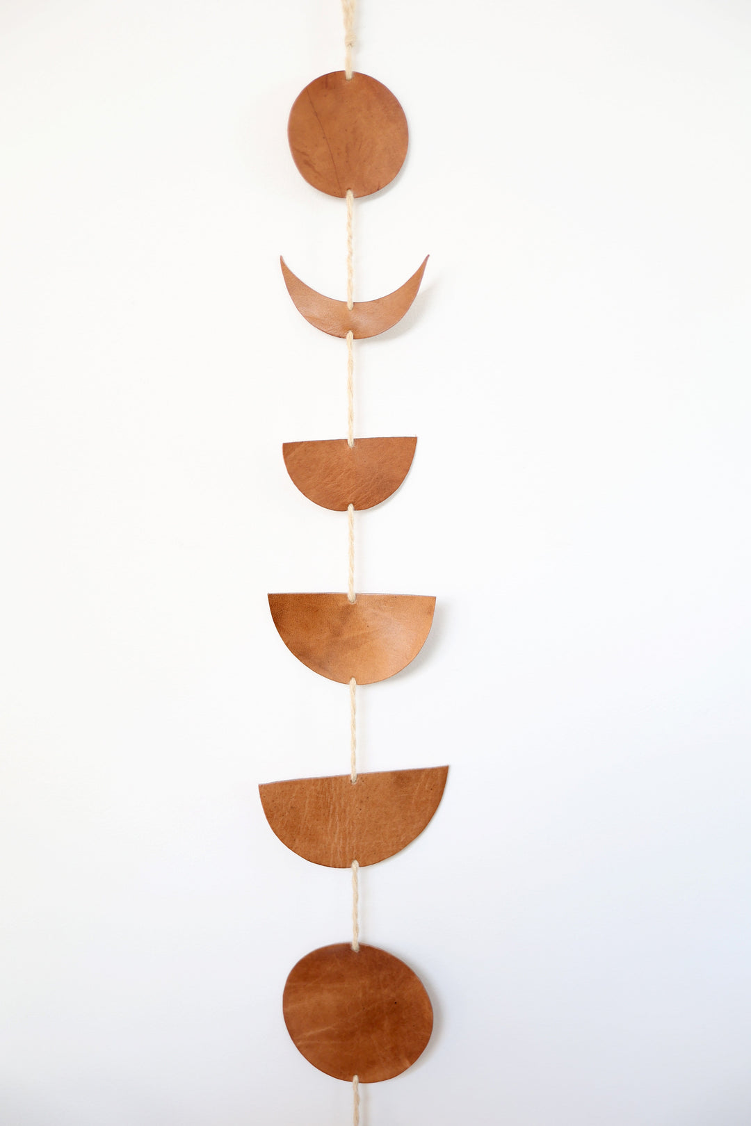 Leather Luna moon-phase garland with hand-cut moon shapes on a cord.