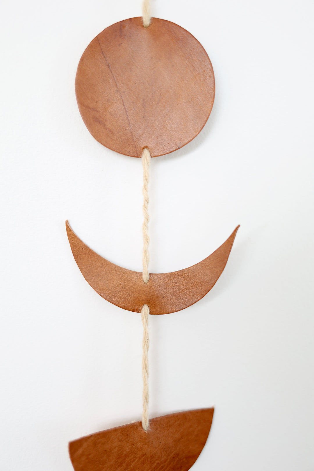 Leather Luna moon-phase garland with crescent and full moon shapes on a neutral background.