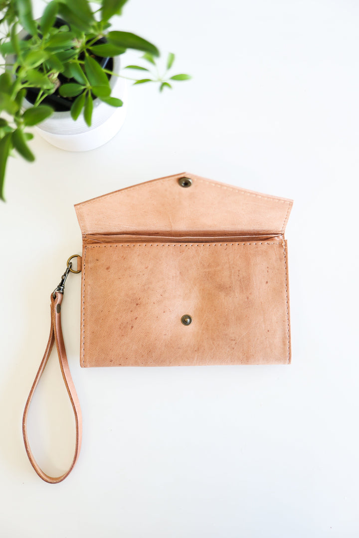 Handmade leather wristlet wallet with stitching and a wrist strap.