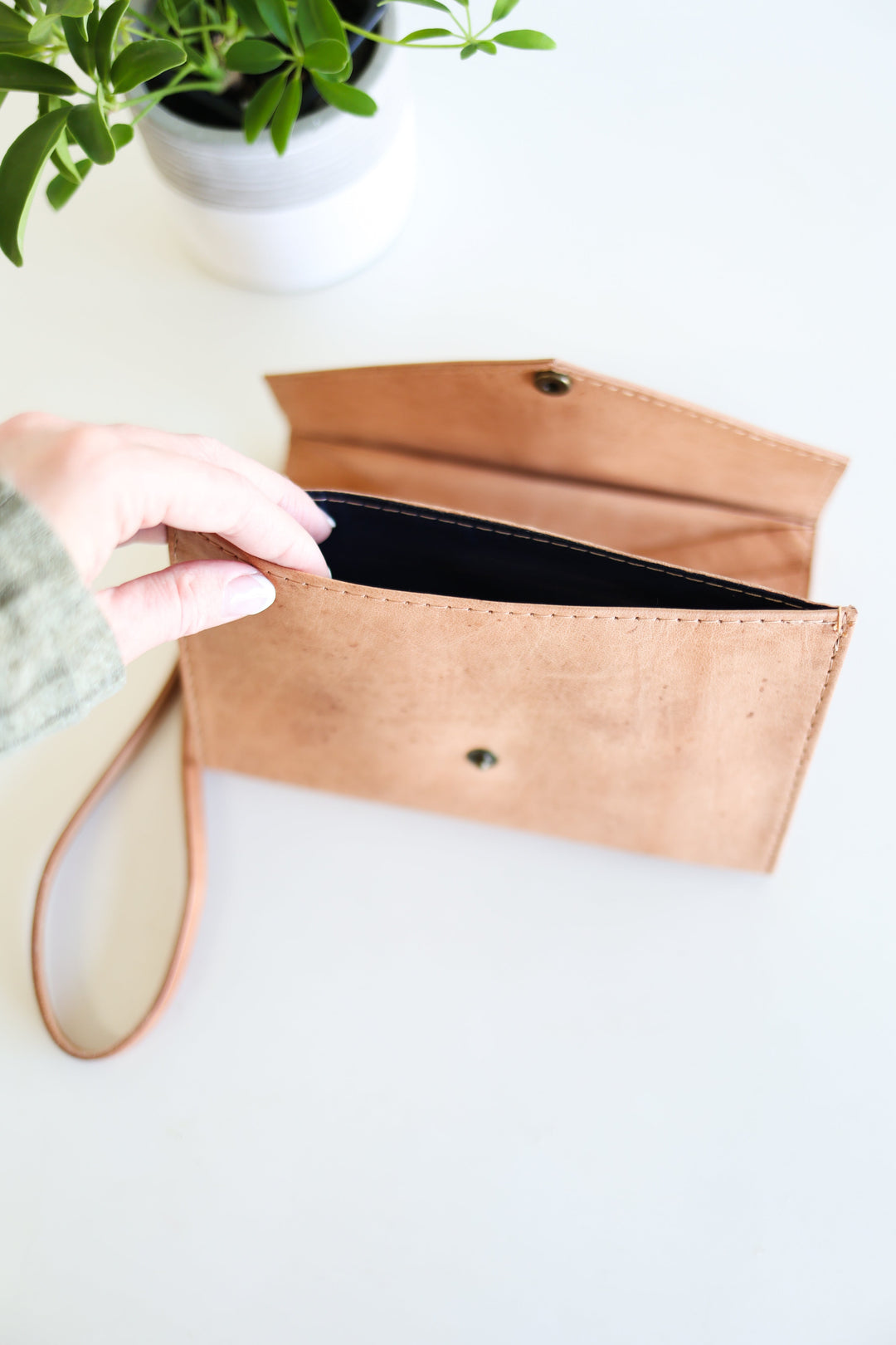 Handmade leather wristlet wallet with stitched leather and a wrist strap.