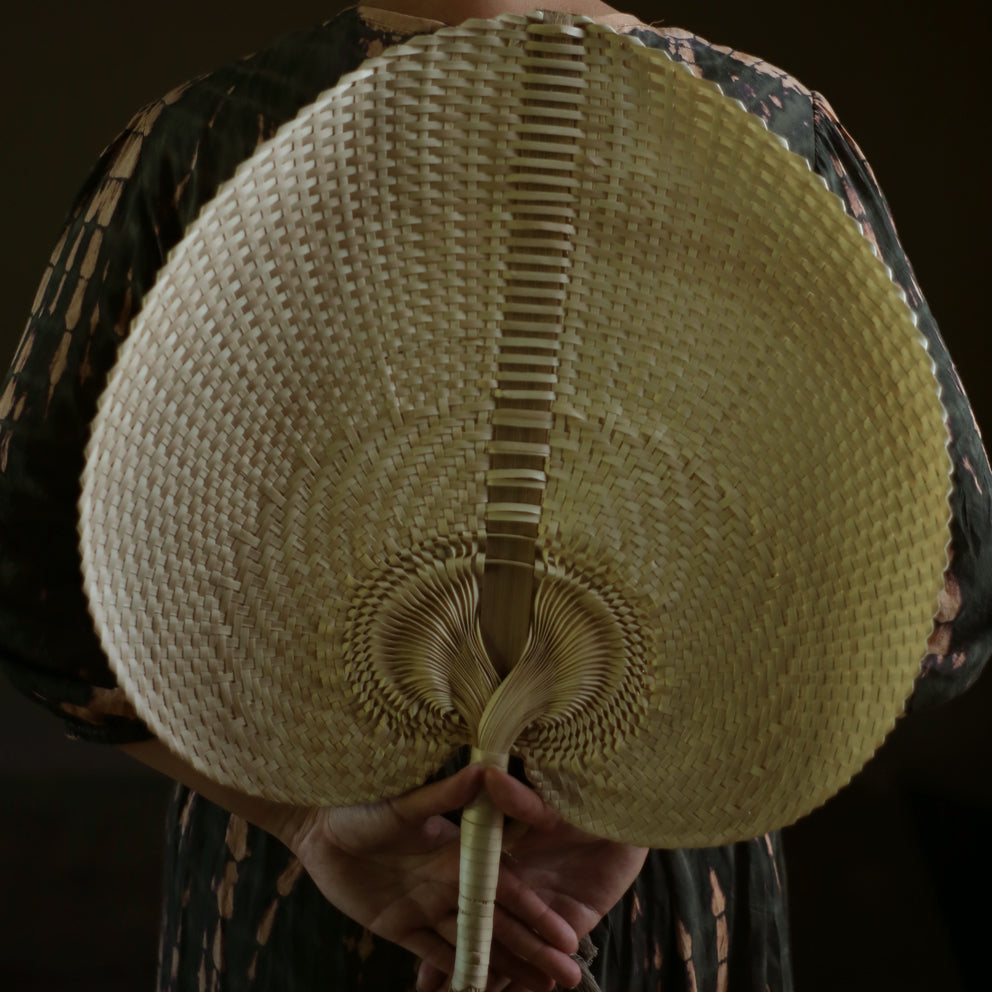 Large Balinese woven hand fan made from lontar palm in neutral tones, showing intricate craftsmanship.