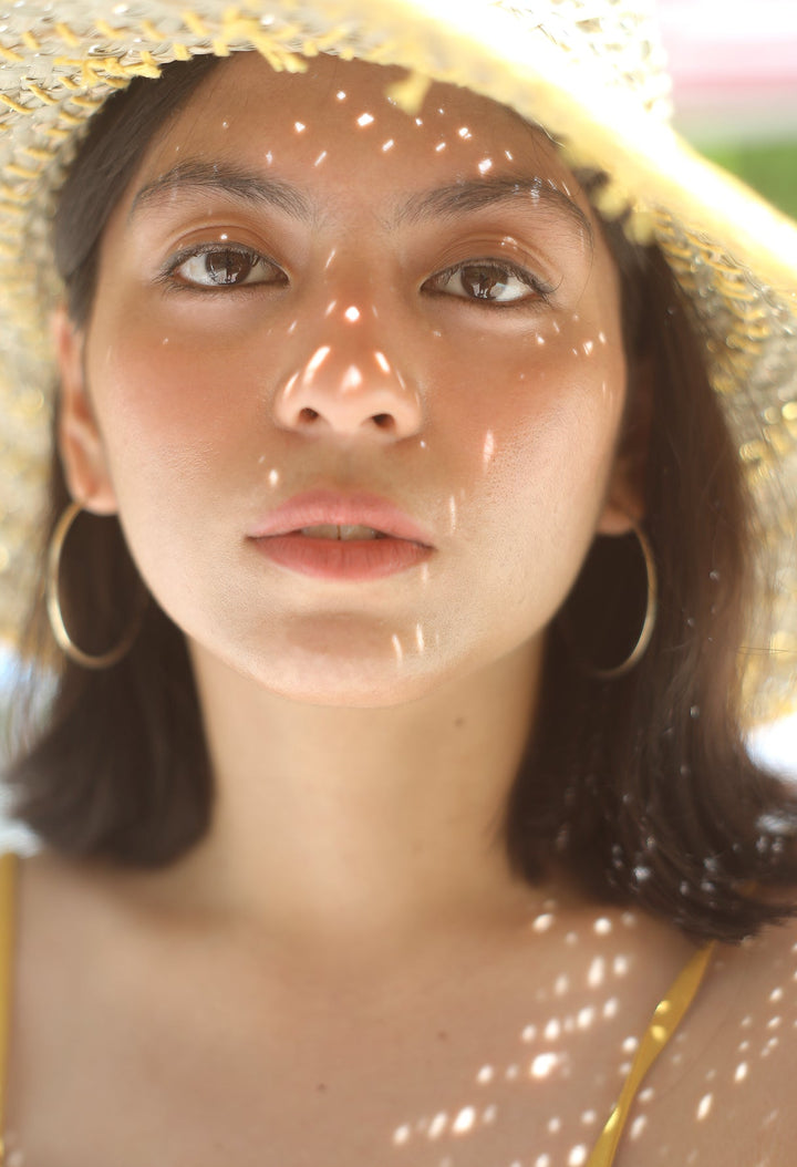 Wide round straw hat in butter yellow with a broad brim and stylish Balinese design.