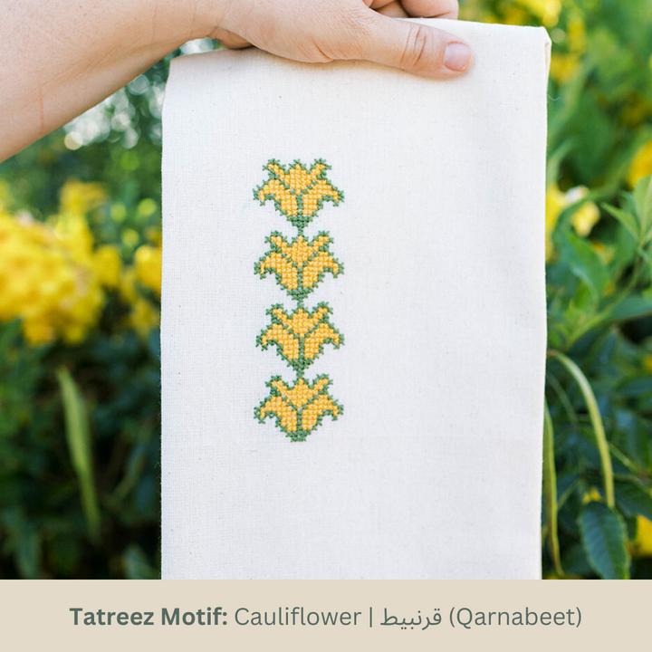 Hand-embroidered tea towel with the Cauliflower tatreez motif in marigold yellow and green on natural cotton.