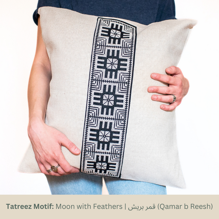 Natural oatmeal pillow cover with a vertical black-and-white Moon with Feathers tatreez panel.