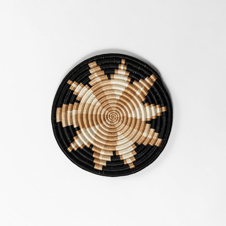 Round handwoven sisal trivets in natural and tea tones on a wooden surface.