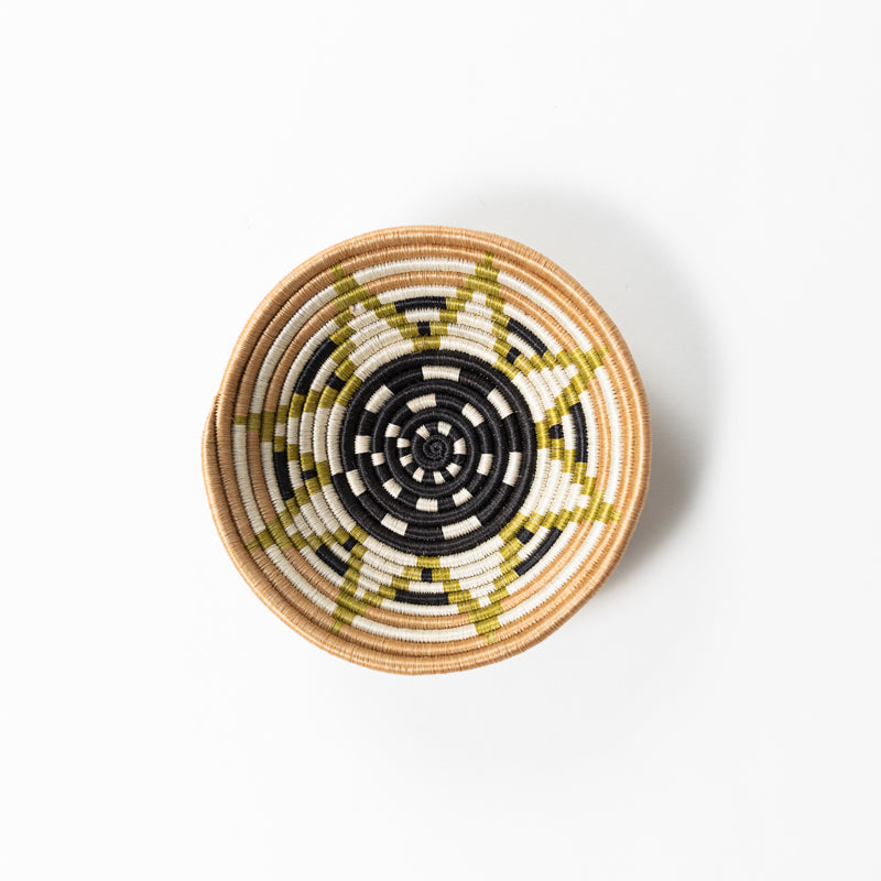 Overhead view of a small Boutique Vestine woven bowl in green, black, and cream.