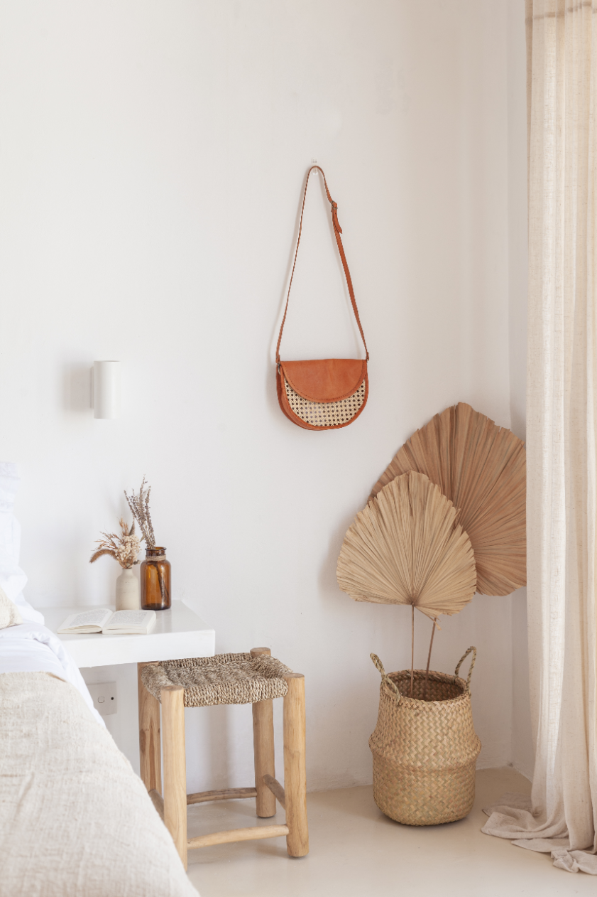 Natural seagrass belly basket holding dried palm leaves in a bedroom corner
