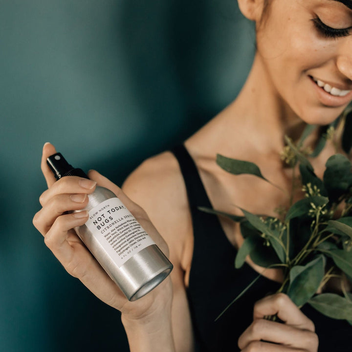 Aluminum bug spray bottle with natural essential oil blend on a neutral background.
