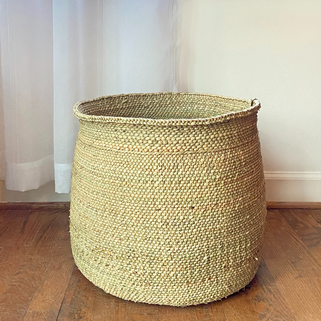 Natural Iringa storage basket, woven Milulu grass filled with household items.