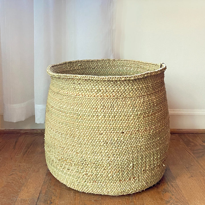 Natural Iringa storage basket, woven Milulu grass filled with household items.