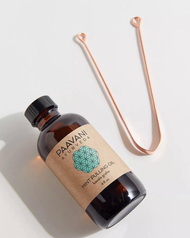 Ayurvedic oral care kit with copper tongue scraper, pulling oil, and pouch.