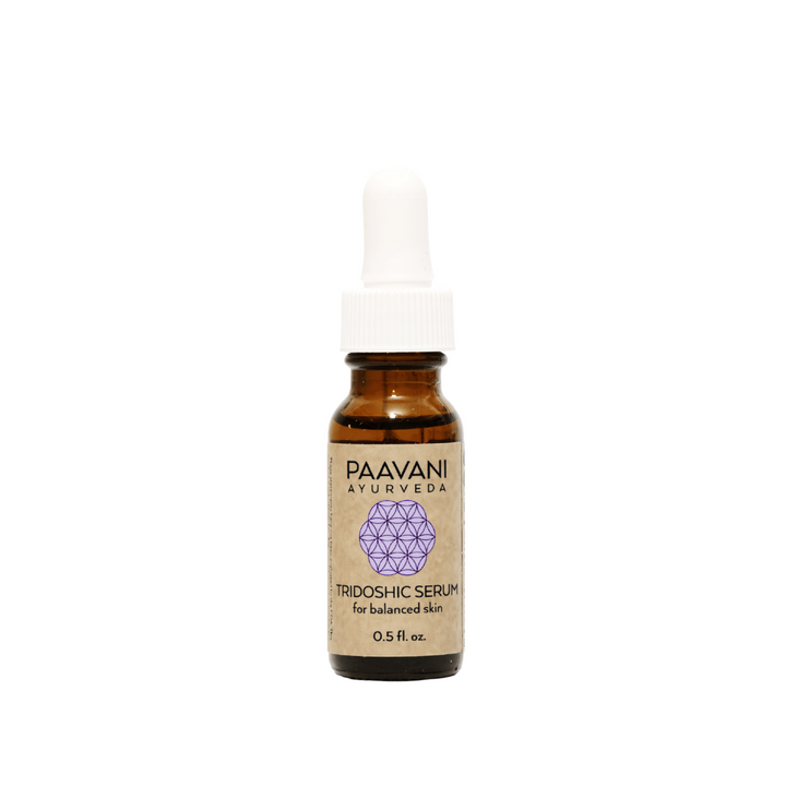 Tridoshic Ayurvedic face serum in a glass dropper bottle with fresh herbs.