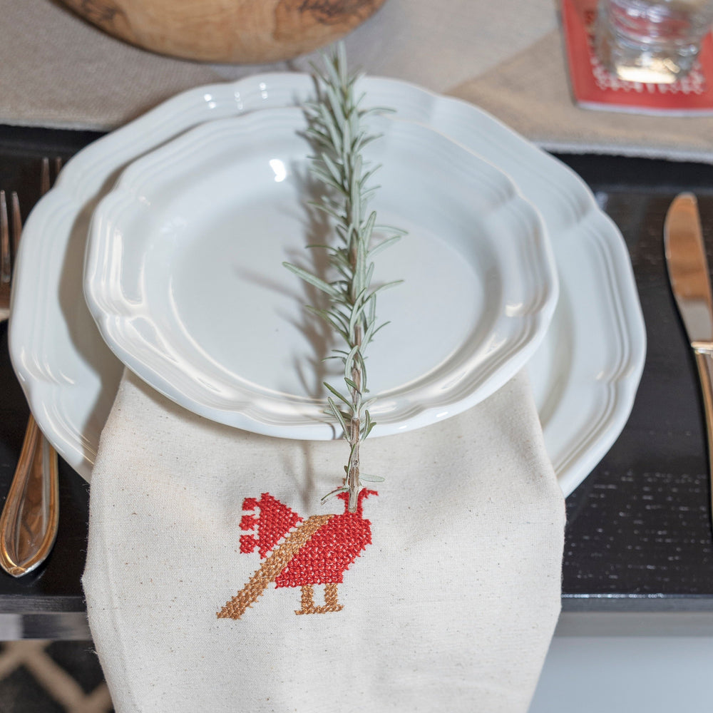 Palestinian tatreez tea towel showing a single red and tan rooster in hand cross-stitch.