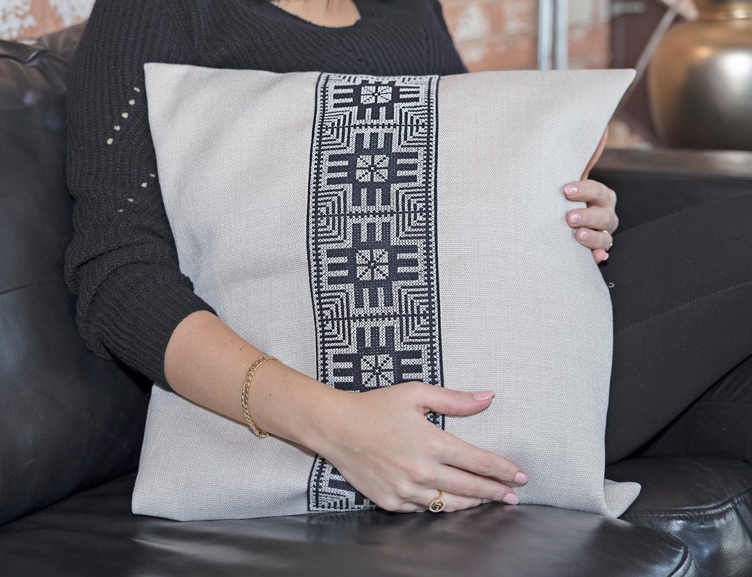 Close-up of the black-and-white Moon with Feathers tatreez embroidery on a natural pillow cover.