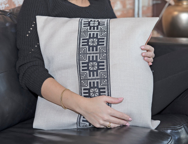 Close-up of the black-and-white Moon with Feathers tatreez embroidery on a natural pillow cover.