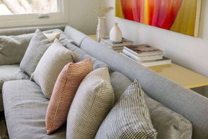Grid weave cotton pillow covers lined along a grey sofa with the rust one in the centre.