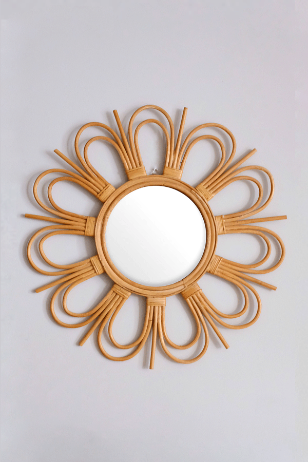 Handcrafted sunburst rattan mirror with a floral design and round glass center.