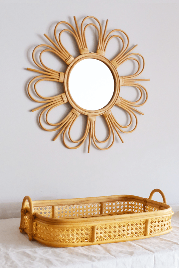 Handcrafted sunburst rattan mirror with a round frame and woven rattan detail.