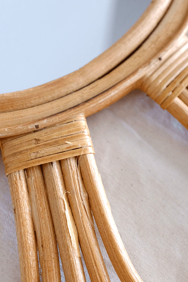 Handcrafted sunburst rattan mirror with a round frame and weaving detail.