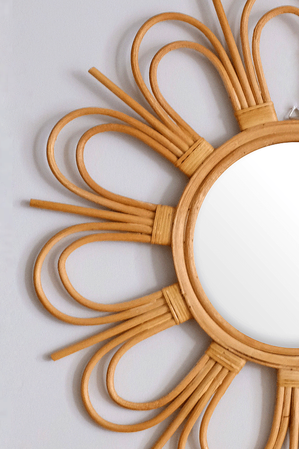Handcrafted sunburst rattan mirror with a circular frame and woven detail.