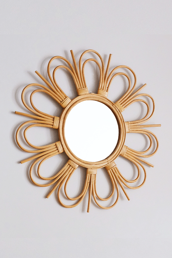 Handcrafted sunburst rattan mirror with a round frame and woven rattan details.