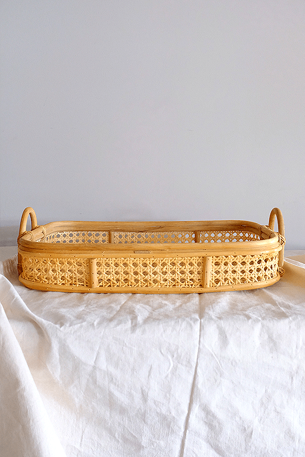 Handwoven rattan tray with intricate cane weaving and handle openings.
