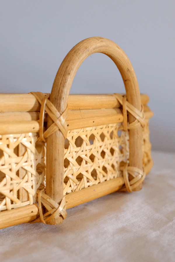 Handwoven rattan tray with handles and an intricate woven pattern.