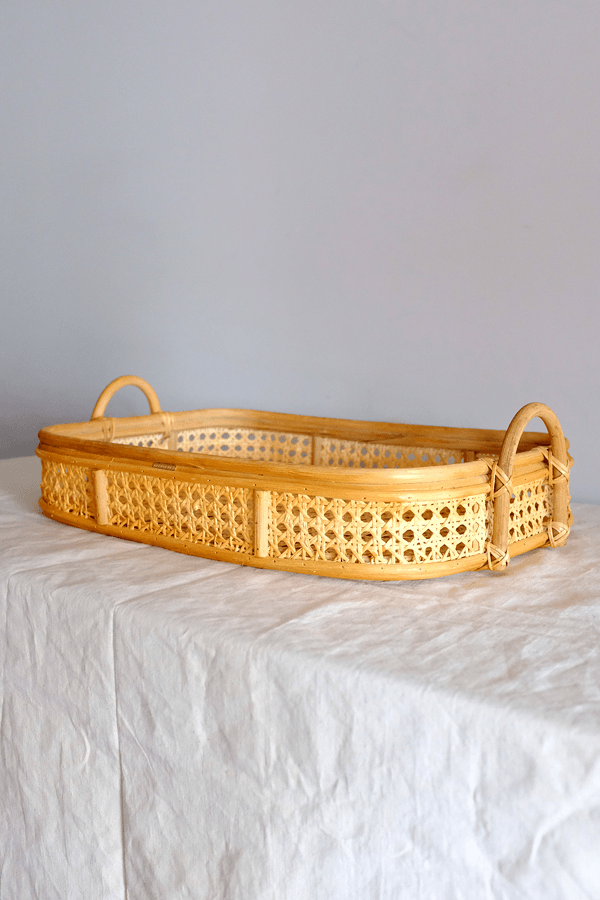 Handwoven rattan tray with a textured woven surface and raised edges.