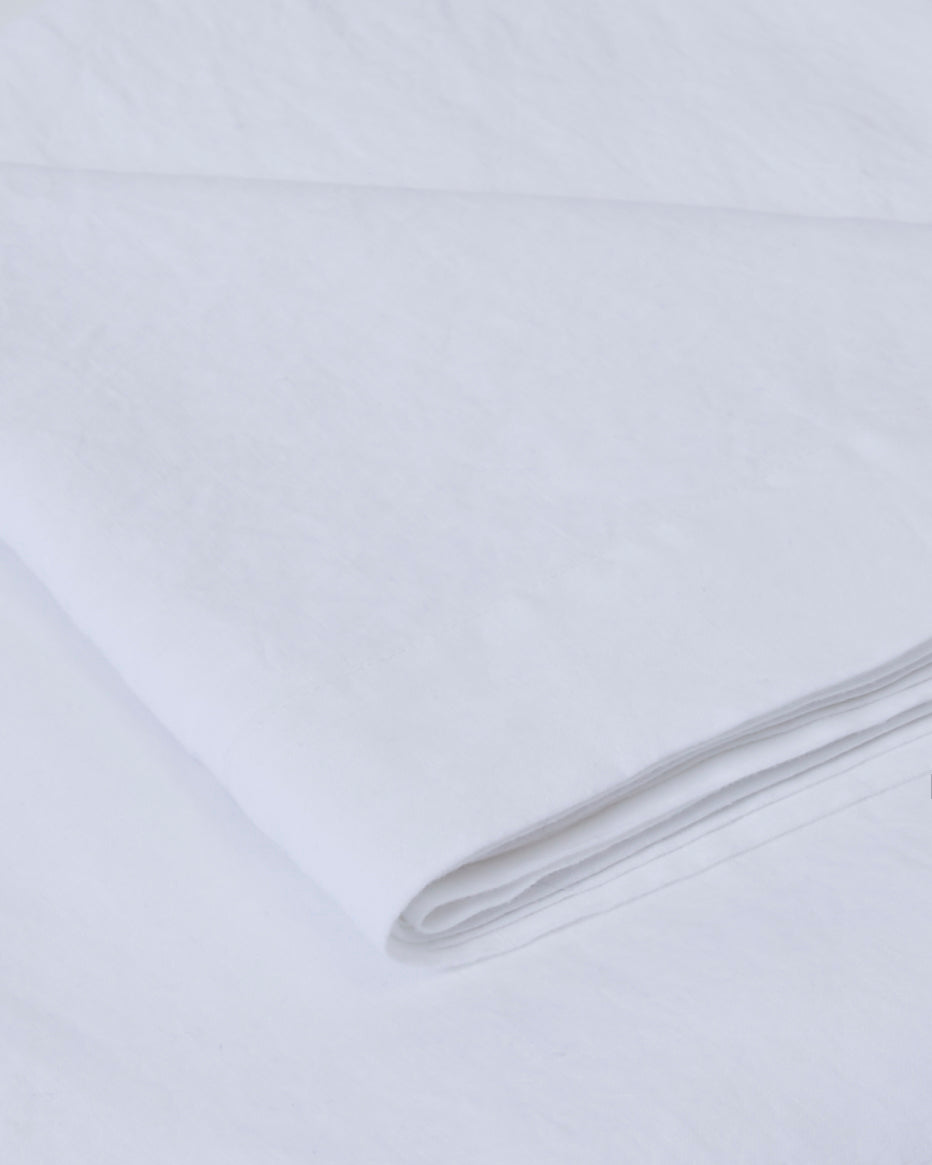 Close-up of a milk-colored linen tablecloth, soft texture and drape.