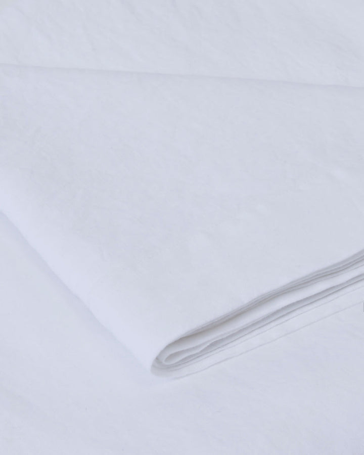 Close-up of a milk-colored linen tablecloth, soft texture and drape.