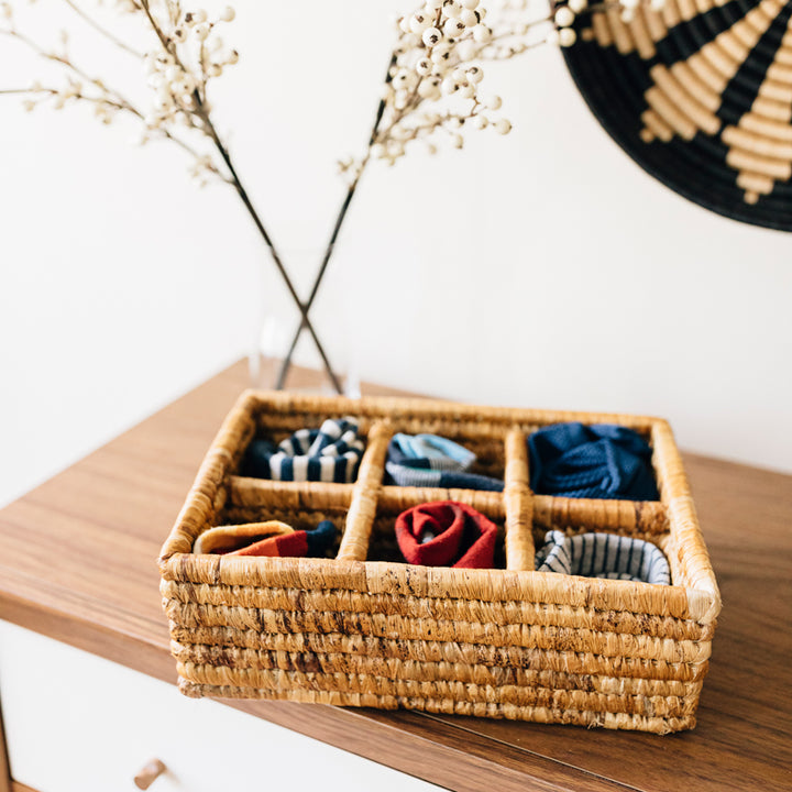Banana leaf divided serving tray with six sections, styled with a woven bowl.
