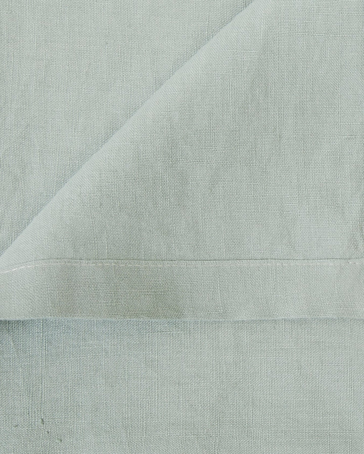 Close-up of four jade linen napkins, showing soft fabric and fold details.