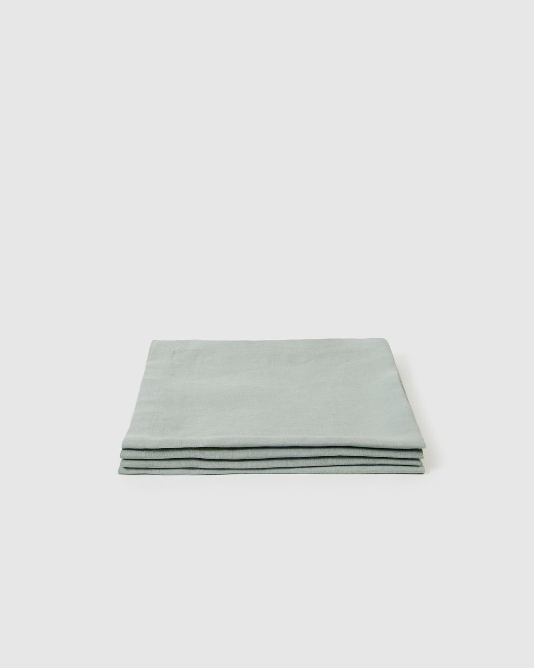 Four jade linen napkins folded neatly, with visible texture and stitching.