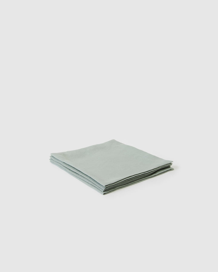 Set of four jade linen table napkins with a soft, textured fabric and folded edges, ideal for elegant dining settings.