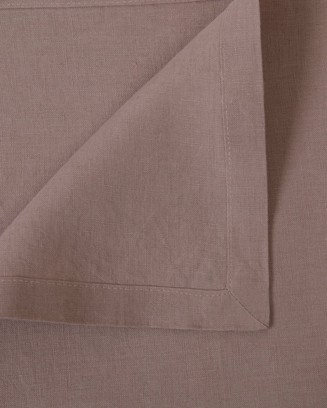 Close-up of four orchid linen napkins, showing fabric and hems.