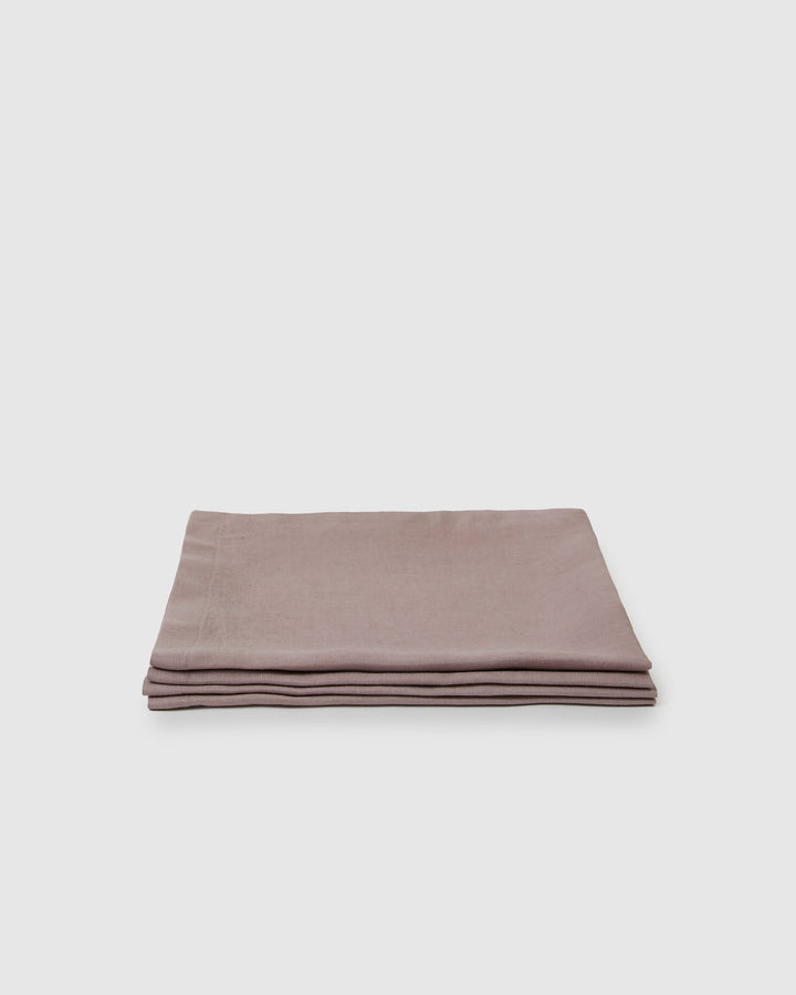 Four orchid linen napkins with natural fabric and stitching.
