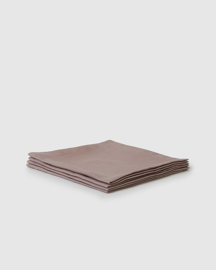 Set of four orchid linen napkins folded on a table, soft fabric texture.