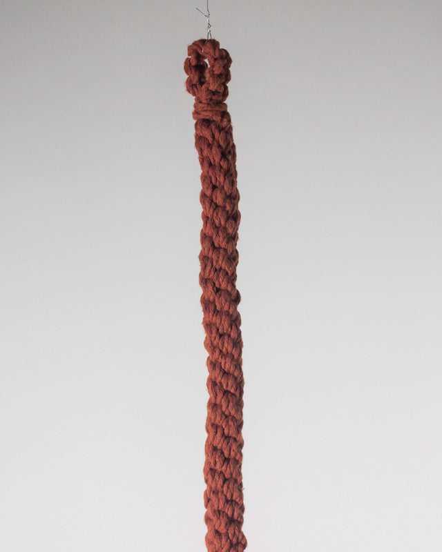Tile-red Bluefields macrame plant holder shown with a potted plant inside.