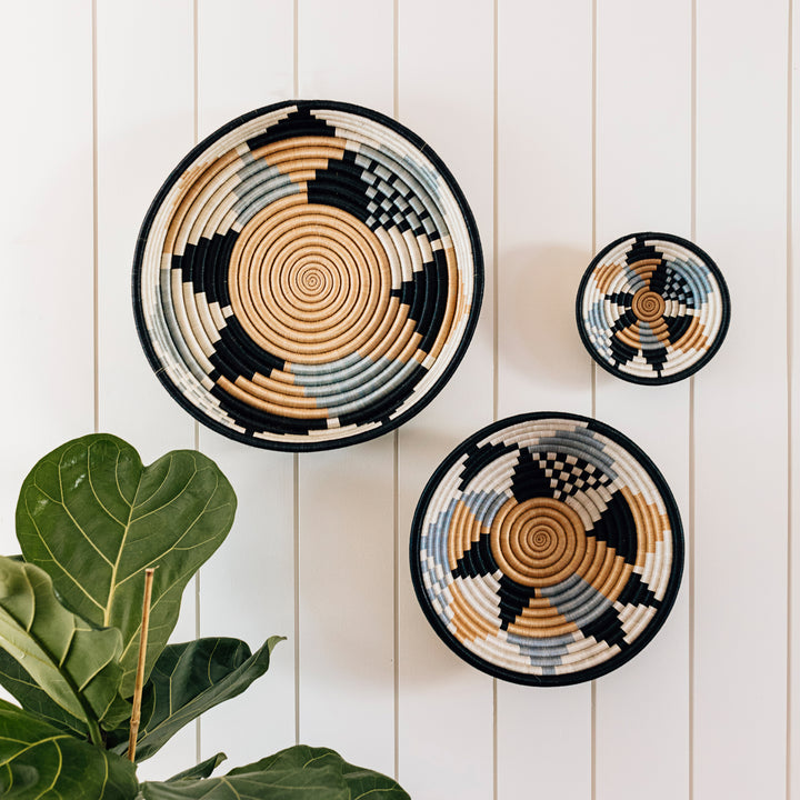 Boutique Diversiform woven bowls in cool gray and slate-blue tones, displayed on a wall.