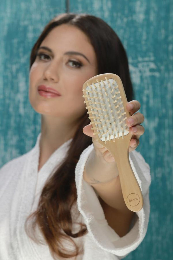 Bamboo detangling hair brush with natural wooden bristles on a white background.
