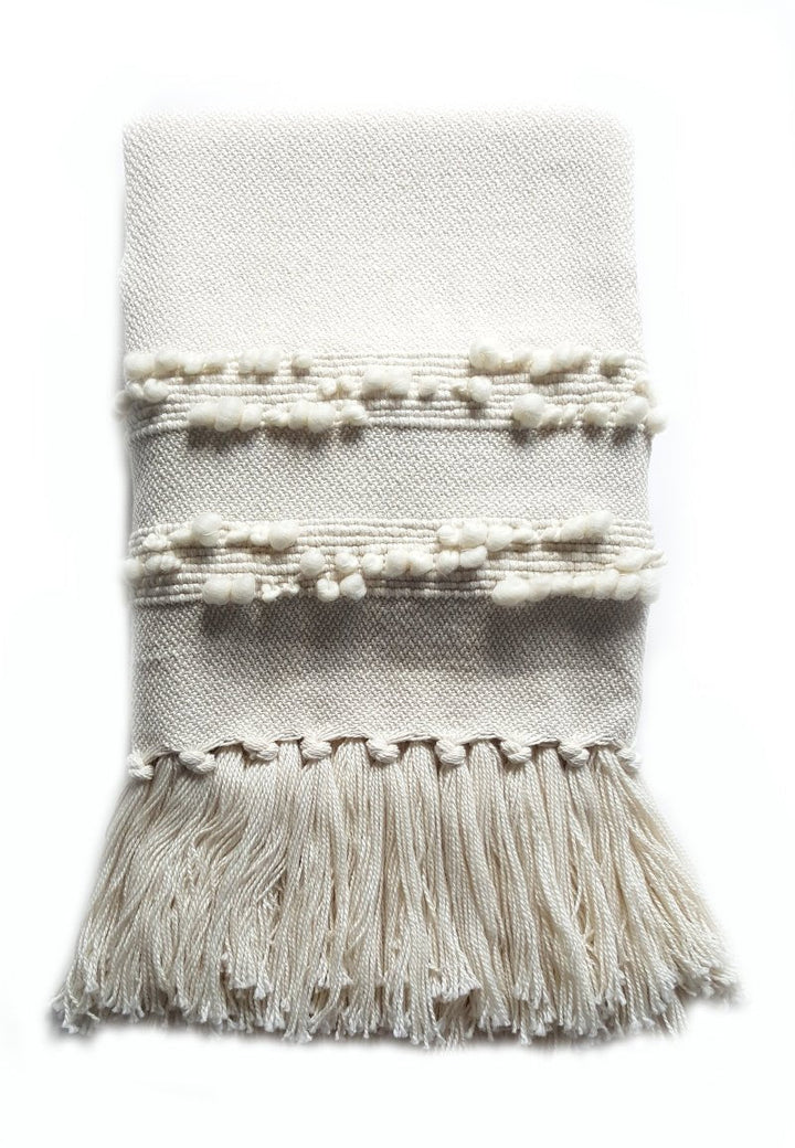 All-ivory merino wool bobble throw folded flat, showing the bobbled bands and hand-knotted fringe.