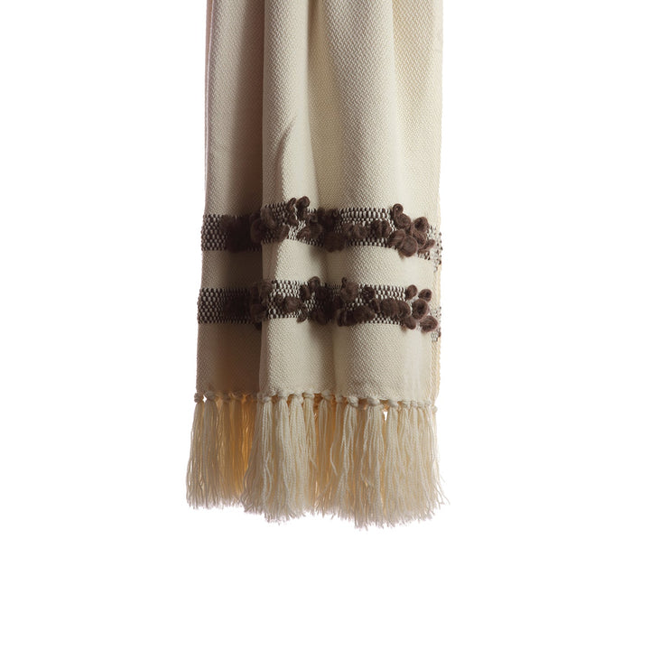 Close-up of the brown bobbled bands and knotted fringe on an ivory wool throw.