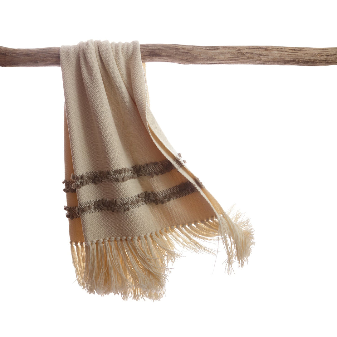 Ivory merino wool throw with grey bobbled bands hanging over a driftwood branch.