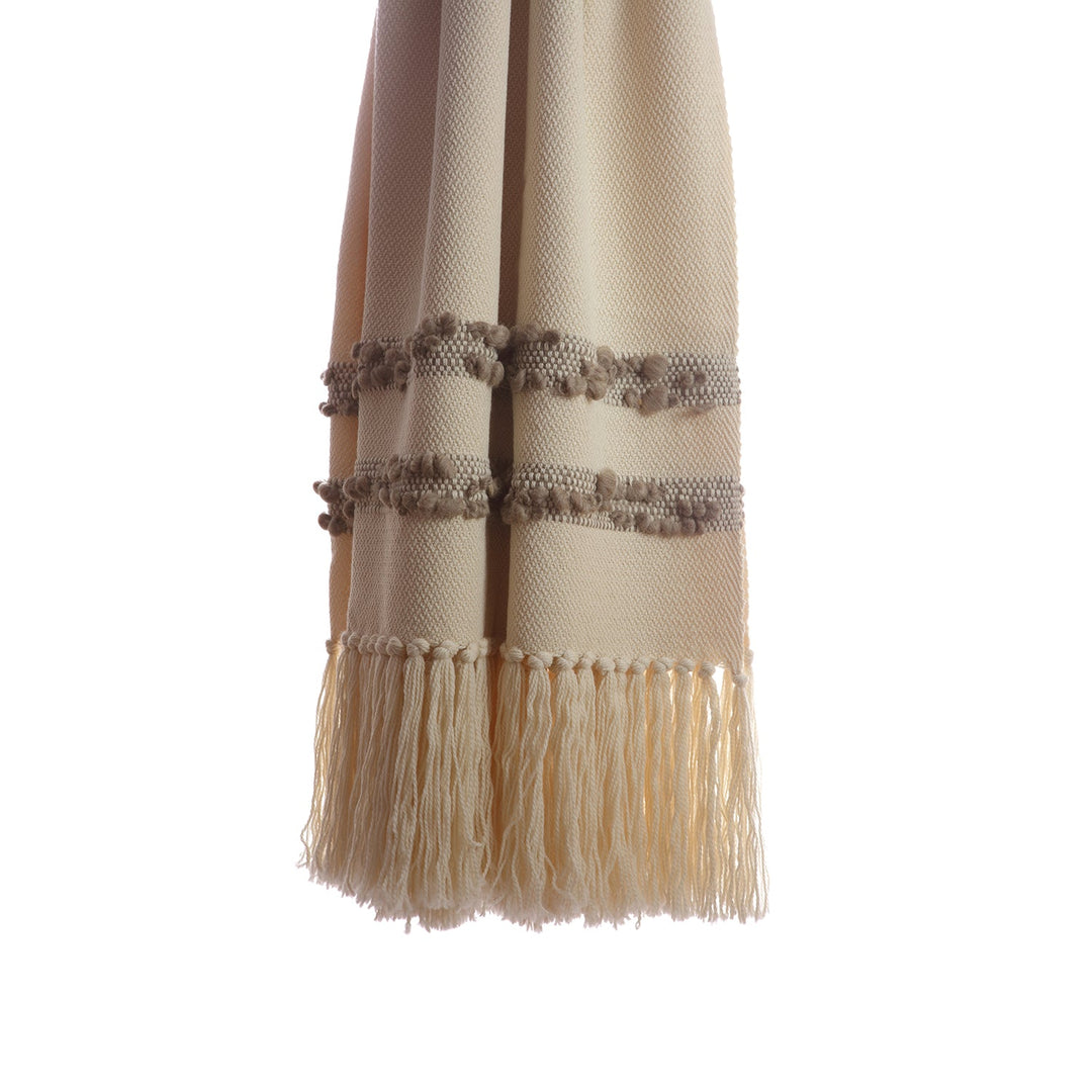 Close-up of the grey bobbled bands and knotted fringe on an ivory wool throw.