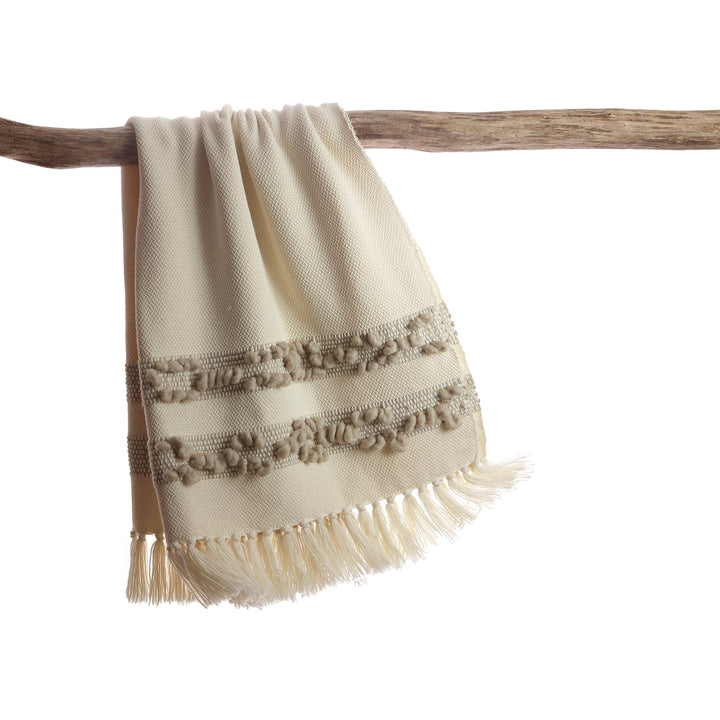 Ivory merino wool throw with grey melange bobbled bands hanging over a driftwood branch.